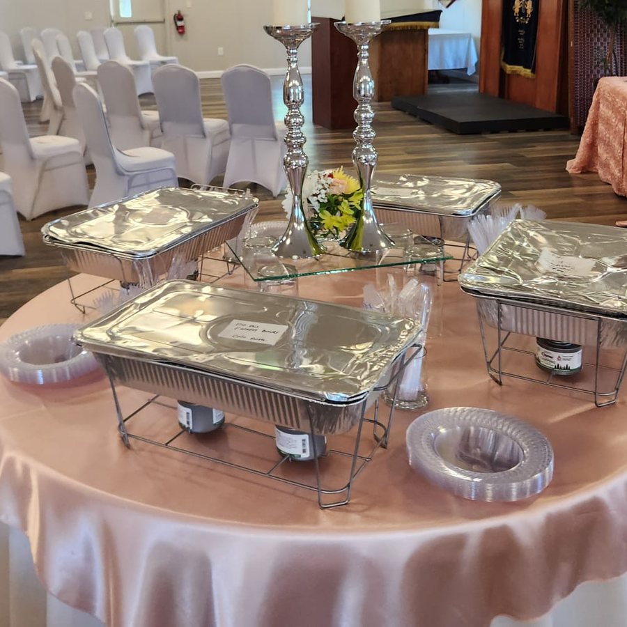 The room dressed for a celebration at Chabad of Venice — chafing trays and silver candlesticks on blush linen