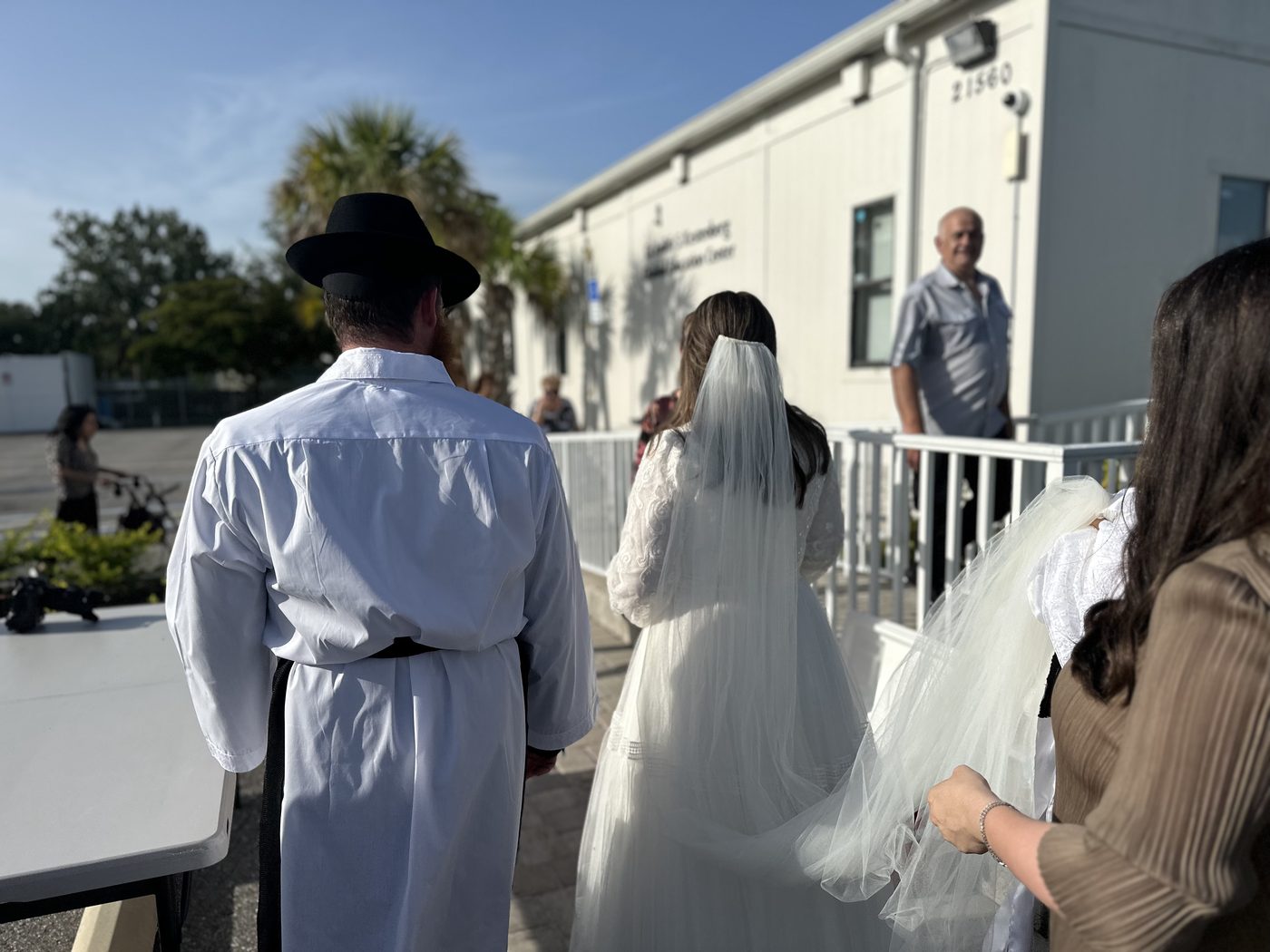 The bride walking toward the chuppah, veil trailing behind her