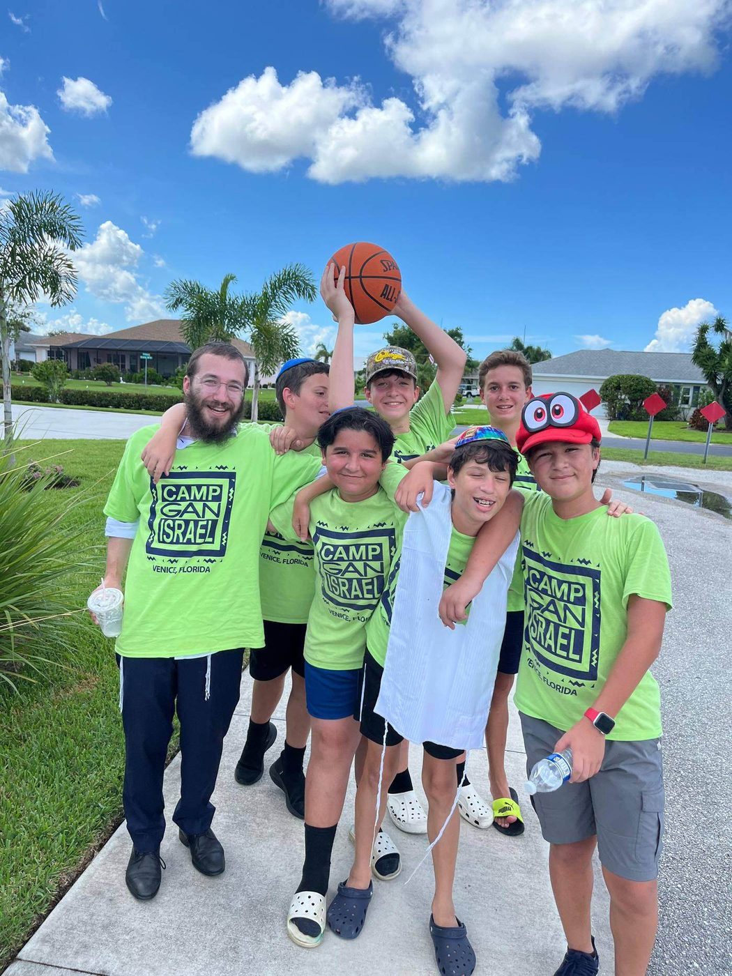 Camp Gan Israel campers in green camp shirts, one holding a basketball