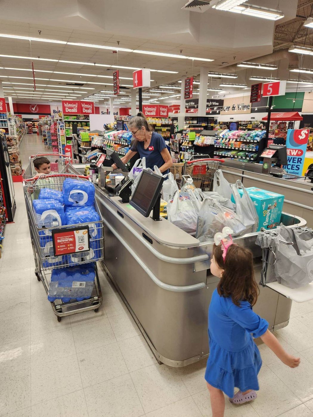 A shopping cart loaded with cases of bottled water at a supermarket checkout