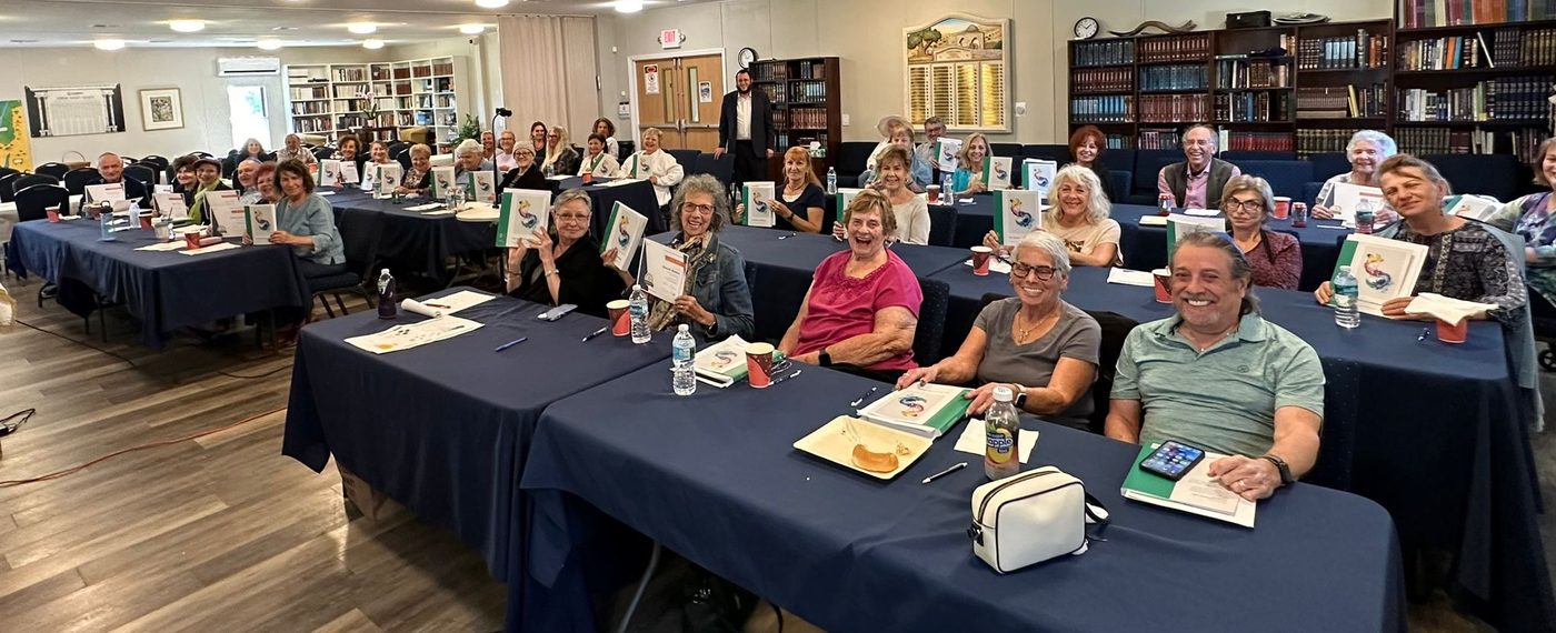 A full room of adults at a JLI course at Chabad of Venice, course books open along the tables