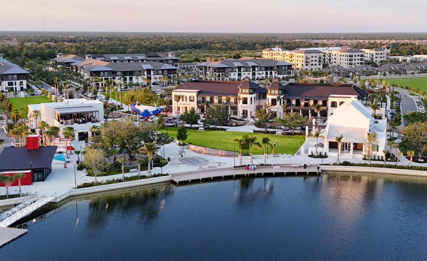Aerial view of Wellen Park's downtown waterfront at sunset, with the lake, boardwalk, and surrounding neighborhoods