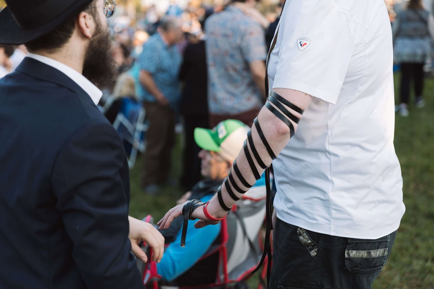 A man's arm wrapped in tefillin straps at a Chabad of Venice gathering