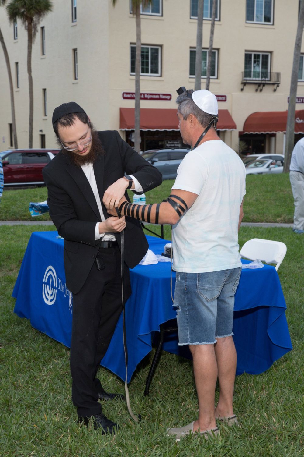Tefillin being put on at an outdoor table at a community event